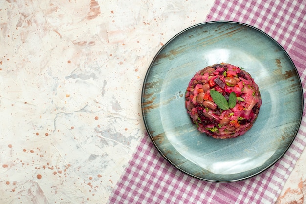 Insalata di vinaigrette vista dall'alto su piatto ovale tovaglia a quadretti bianca viola su tavolo grigio chiaro posto copia