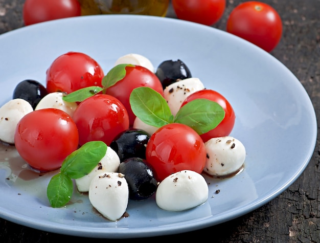 Insalata fresca con pomodorini, basilico, mozzarella e olive nere.