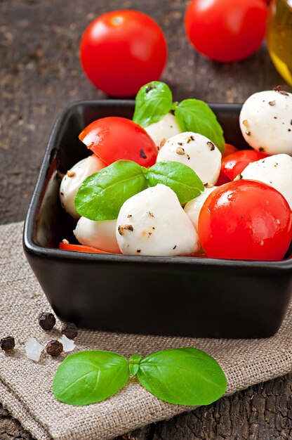 Insalata fresca con pomodorini, basilico, mozzarella e olive nere.