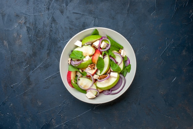 Insalata fresca tritata vista dall'alto in una ciotola sfondo blu scuro