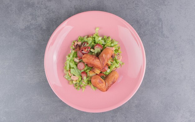 Insalata golosa con salsiccia, sulla superficie di marmo