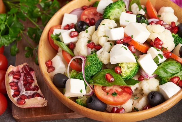 Insalata greca o horiatiki con grandi pezzi di pomodori, cetrioli, cipolla, formaggio feta e olive in vista dall'alto isolato ciotola bianca. Insalata di paese con mozzarella a dadini, rucola, prezzemolo e olio d'oliva