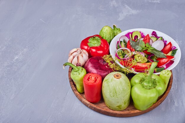 Insalata leggera con verdure ed erbe aromatiche in piatto di legno.