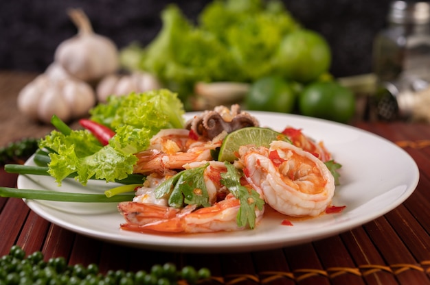 Insalata piccante di calamari e gamberetti in un piatto bianco con limone, coriandolo e lattuga