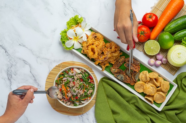 Insalata piccante mista con salsiccia vietnamita, uova conservate e calamari croccanti, cibo tailandese.