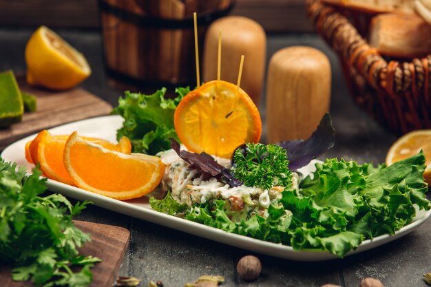 Insalata russa di stolichni con lattuga e fette d'arancia.