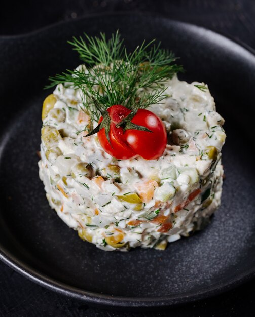 Insalata russa di stolichni con pomodoro e aneto in cima.