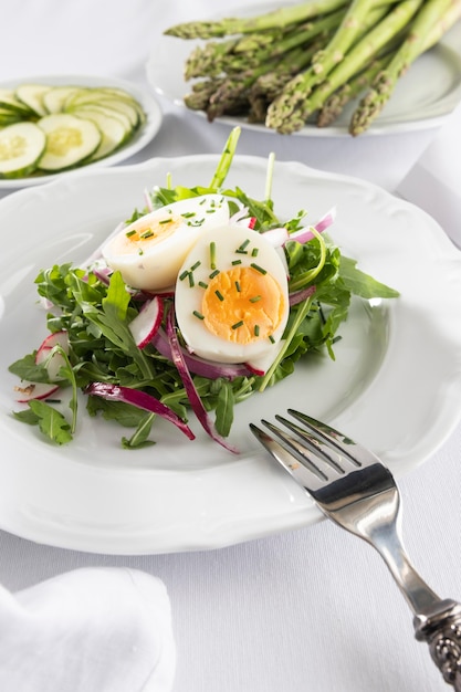 Insalata sana con l'uovo su una composizione bianca del piatto