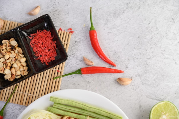 Insalata tailandese della papaia in un piatto bianco con il peperoncino rosso, la calce e l'aglio.