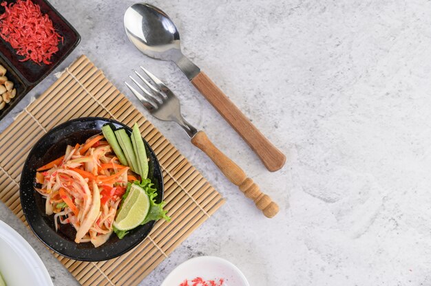 Insalata tailandese della papaia in un piatto bianco con riso appiccicoso e gamberetti essiccati