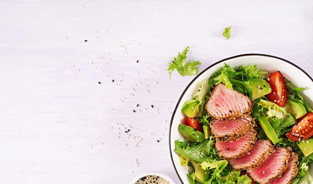 Insalata tradizionale giapponese con pezzi di tonno Ahi alla griglia medio-raro e sesamo con verdure fresche su una ciotola.