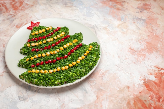 Insalata verde a metà vista a forma di albero di Natale all'interno del piatto su sfondo chiaro