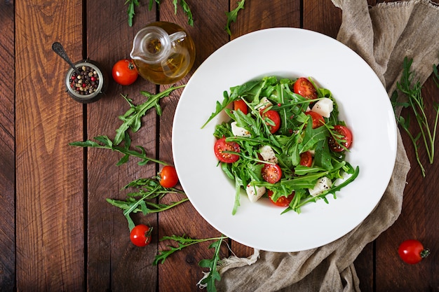 Insalata vitaminica di pomodori freschi, rucola, formaggio feta e peperoni. Menu dietetico. Nutrizione appropriata. Vista dall'alto. Disteso.