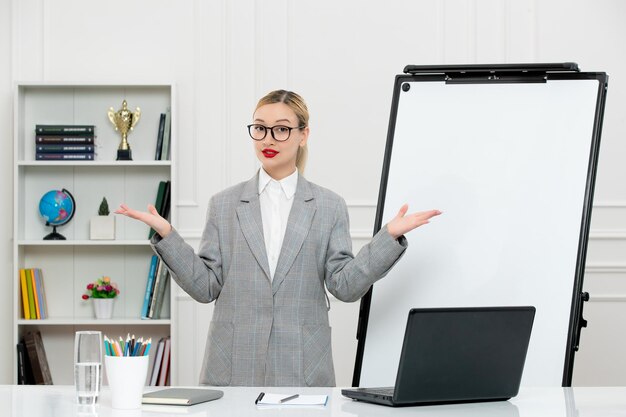 Insegnante carino istruttore in tuta in classe con computer e lavagna con gli occhiali