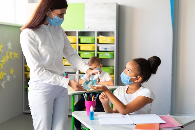 Insegnante che disinfetta le mani dei bambini