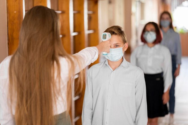 Insegnante che misura la temperatura corporea a scuola