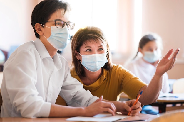 Insegnante con maschera che spiega agli studenti