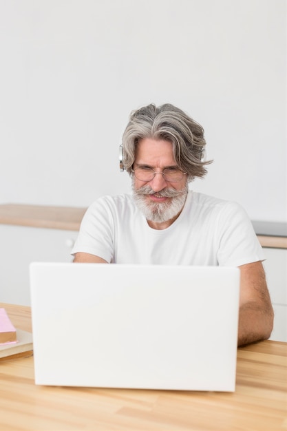 Insegnante del mezzo colpo allo scrittorio facendo uso del computer portatile