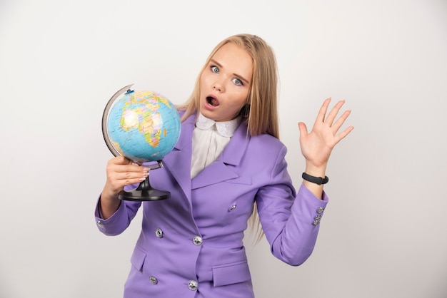 Insegnante della donna con il globo che posa sul bianco.