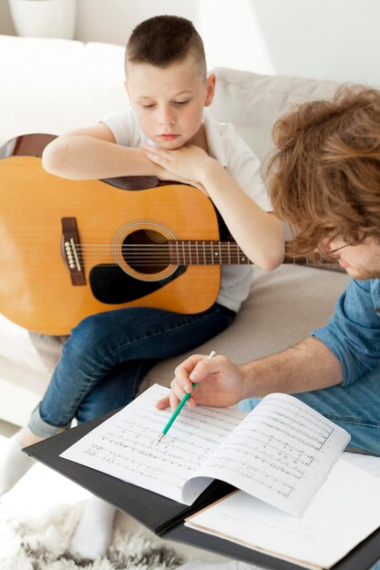 Insegnante di alta vista e ragazzo a suonare la chitarra