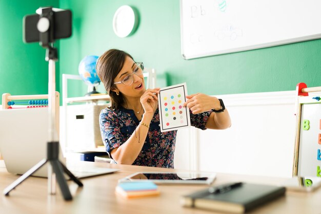 Insegnante di scuola materna che usa le flashcard per insegnare i colori ai bambini. Bambini dell'asilo che imparano su una classe virtuale