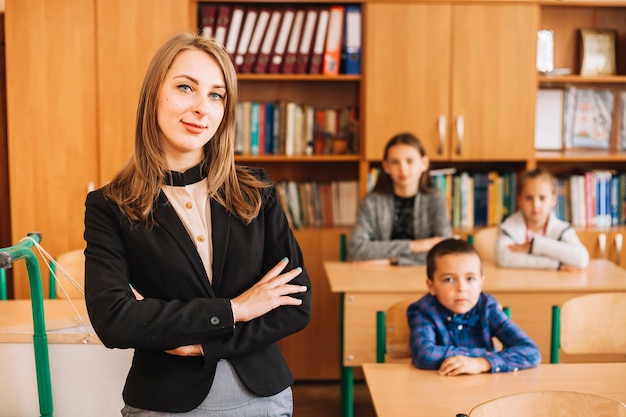 Insegnante di scuola su priorità bassa di sedersi a studenti scrivania