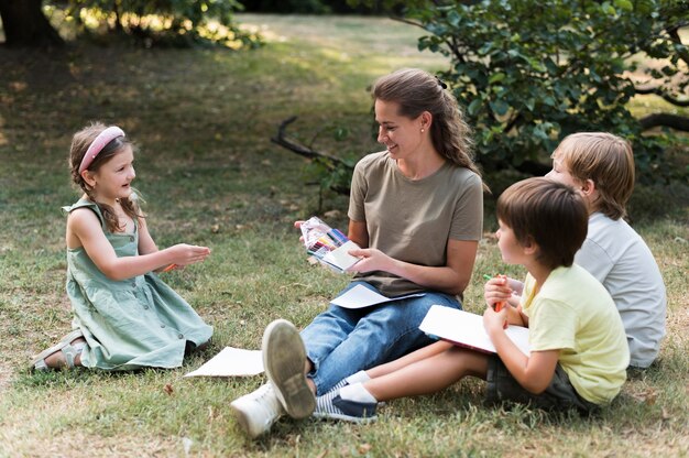 Insegnante e bambini seduti sull'erba