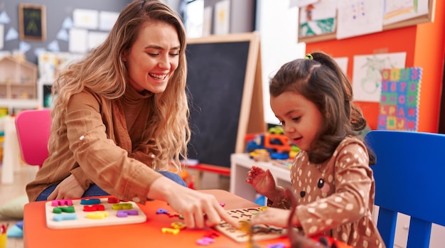 Insegnante e bambino che giocano con il gioco di puzzle matematico seduto sul tavolo all'asilo