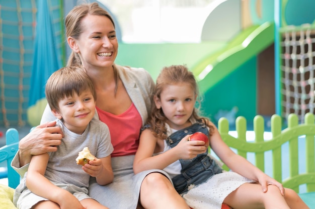 Insegnante felice del colpo medio che tiene i bambini