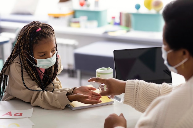 Insegnante femminile che insegna ai bambini a disinfettare