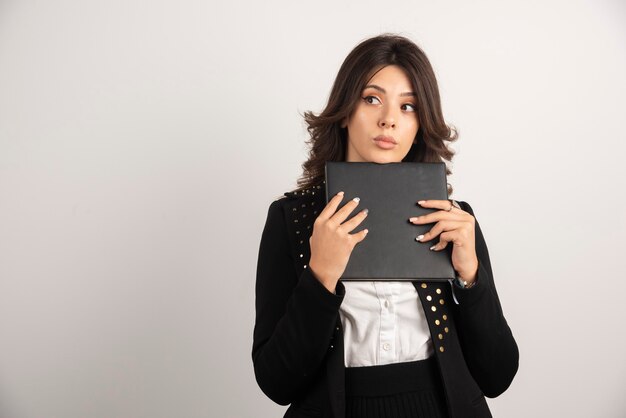 Insegnante femminile con il libro che pensa sul bianco.