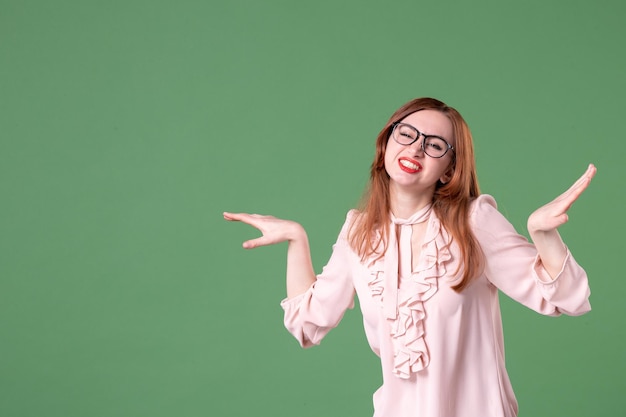 Insegnante femminile di vista frontale in camicetta rosa che posa su sfondo verde lavoro biblioteca scuola donna giovane colore libro lezione studenti lavoratori universitari