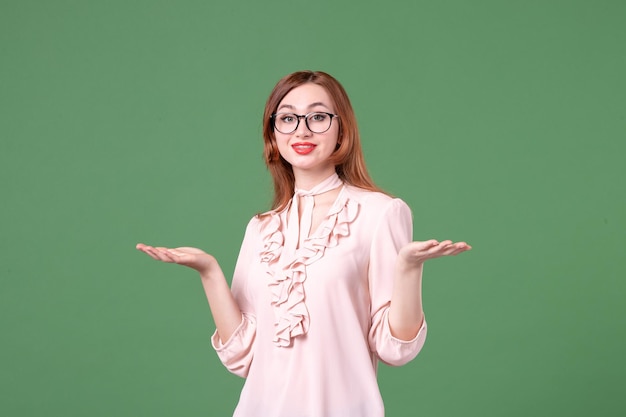 Insegnante femminile di vista frontale in camicetta rosa su sfondo verde biblioteca scolastica lezione universitaria libro di lavoro a colori studente giovane donna