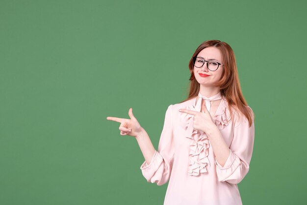 Insegnante femminile di vista frontale in camicetta rosa su sfondo verde scuola libro a colori biblioteca studente universitario giovane lezione lavoro donna