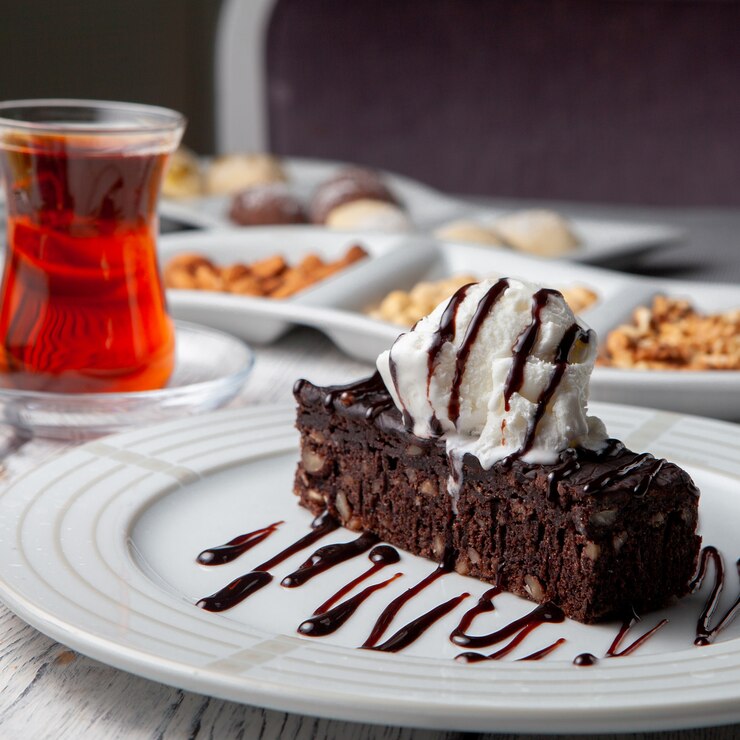 Foto gratuito insieme di tè, noci e dessert in un piatto su un fondo di legno bianco. vista laterale.