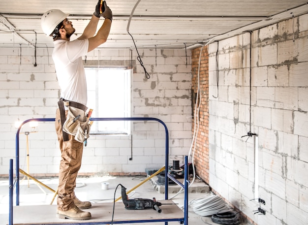 Installatore elettricista con uno strumento nelle sue mani, lavorando con il cavo in cantiere