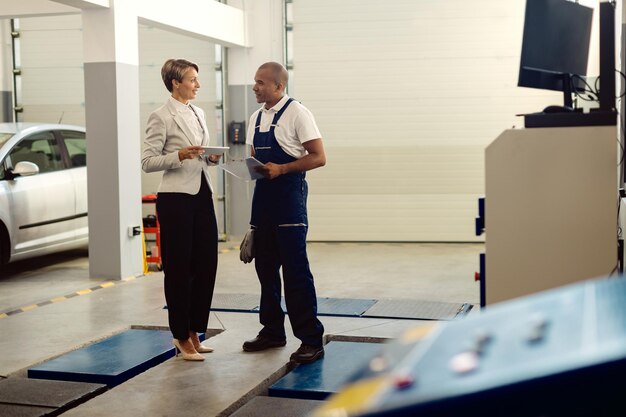 Integrale del meccanico e della donna di affari afroamericani che comunicano all'officina riparazioni auto