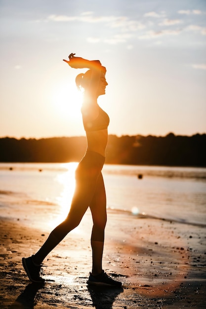 Integrale della donna atletica felice che gode all'alba alla riva del fiume