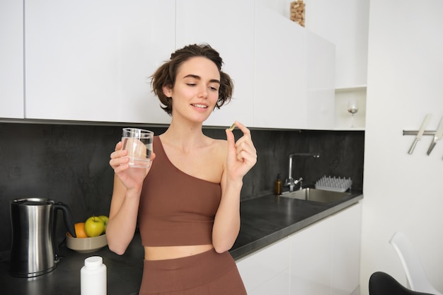 Integratori alimentari e stile di vita sano giovane donna che assume vitamina cd omega con un bicchiere d'acqua s