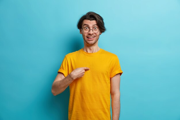 Intendi me. L'uomo caucasico allegro indica se stesso guarda sorprendentemente alla macchina fotografica sorpreso di essere menzionato da qualcuno