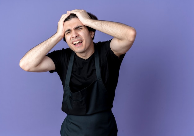 interessato giovane uomo bello barbiere in uniforme afferrò la testa isolata sul blu