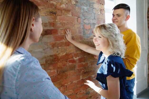 Interior designer che lavora con una giovane coppia. Bella famiglia e designer professionista o architetto che discute del concetto di interni futuri, lavorando con la tavolozza dei colori, i disegni delle stanze in un ufficio moderno.