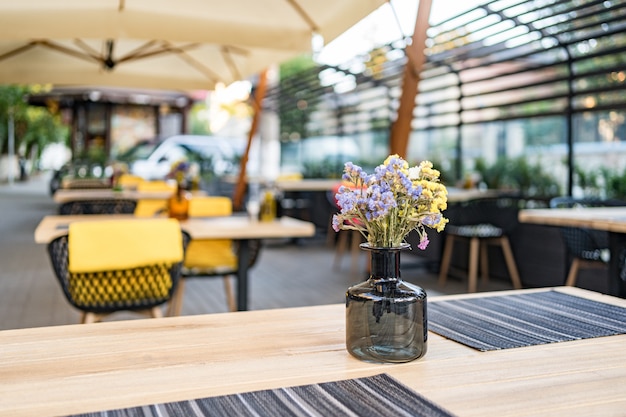 Interiore del caffè di strada di estate in strada, ornato con alberi decorativi e ombrelloni