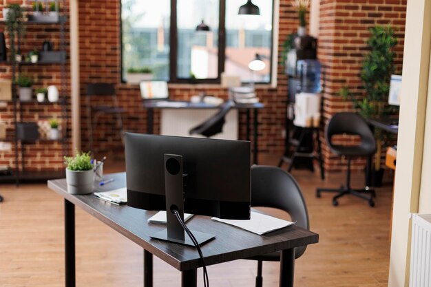 Interno dell'ufficio aziendale vuoto con mobili e nessuno. Area di lavoro moderna dell'agenzia di marketing aziendale con scrivanie contemporanee e computer desktop che visualizzano grafici finanziari.