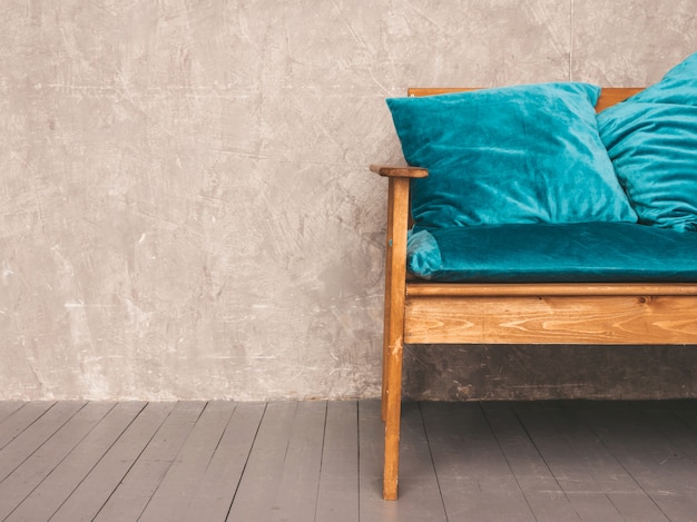 Interno muro grigio con elegante divano moderno imbottito in legno e blu