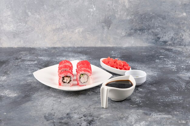 Involtini californiani con caviale di pesce volante su piatto bianco con zenzero e wasabi
