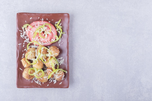 Involtini di prosciutto e patate fritte sul piatto scuro.