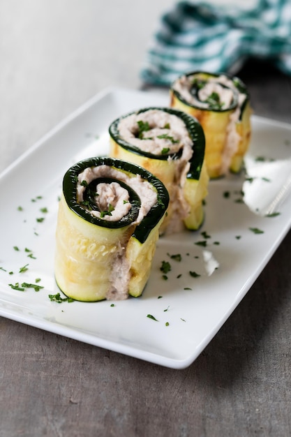 Involtini di zucchine alla griglia ripieni di crema di formaggio e tonno su tavola di legno Primo piano