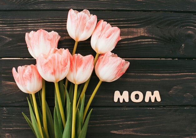 Iscrizione di mamma con bouquet di tulipani sul tavolo di legno