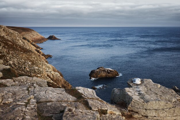 Isola di formazione rocciosa vicino a rocce costiere sotto le nuvole nimbus